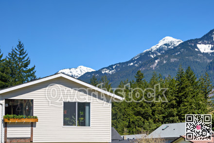 Top of average residential house with mountain view on blue sky background
