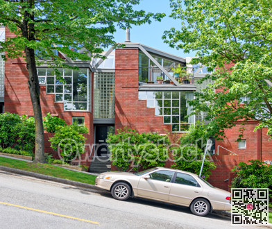 Residential townhouses on the street going uphill with a car parked in front