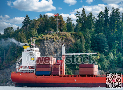 Container freight vessel is passing by Stanley Park in Vancouver harbor
