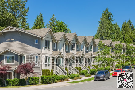 Street of new townhouses with cars parked on the road.
