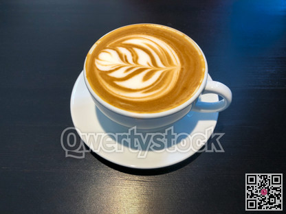 White cap of coffee latte on a black desk surface