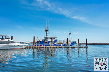 Small fishing trawler and whte yacht moored at the ocean pier