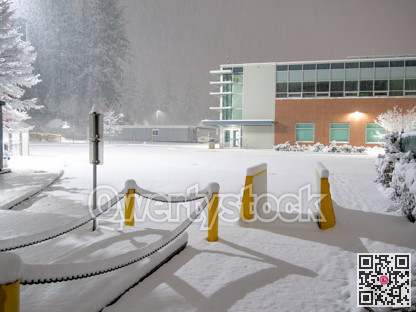Office building with a parking lot covered in snow under the night lights