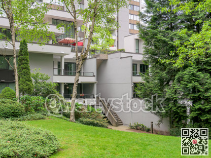 Complex of residential buildings with green lawn and trees in front
