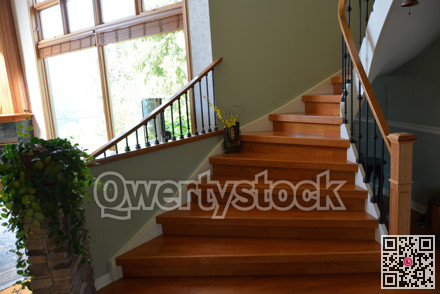 Wooden interior stairway of luxury residential house with railings.