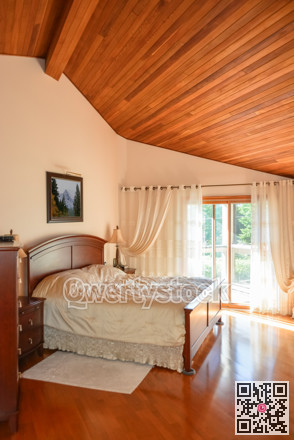 Beautiful bedroom with wooden ceiling and sun light coming through glass door.