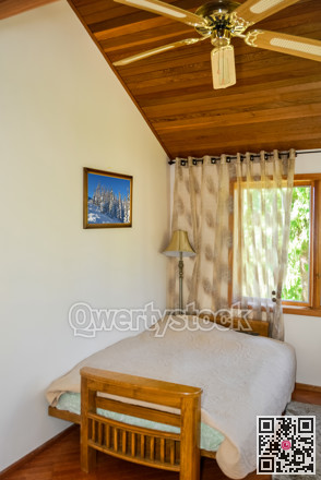 Small lightful bedroom with curtains on windows and rug on the floor.