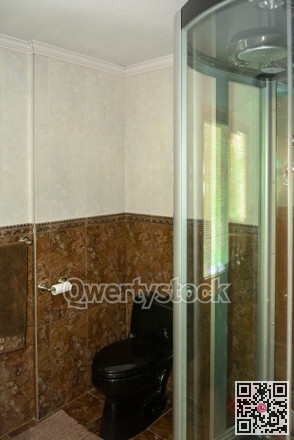 Automated shower cabin and black toilet in a bathroom of luxury house.
