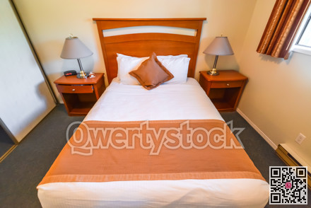 Interior of hotel bedroom with double bed and lamps on bedside tables.