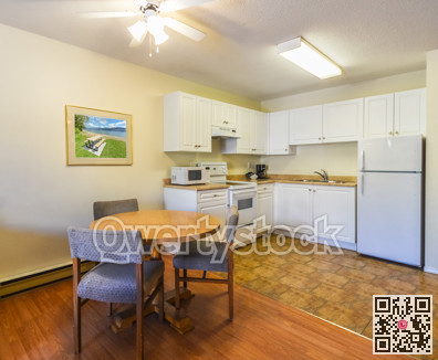 Modest white kitchen with the table and chairs in dinner area.
