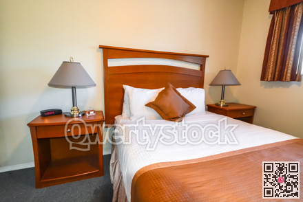 Interior of bedroom with radio watch, perfume vail, and lamps on bedside tables.