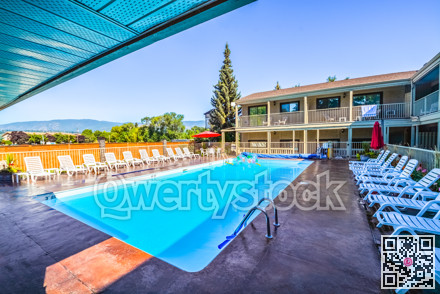 A hotel swimming pool with chaise lounges on side.