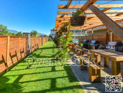 Barbecue and picnic area of hotel with row of tables and grills under the shed.