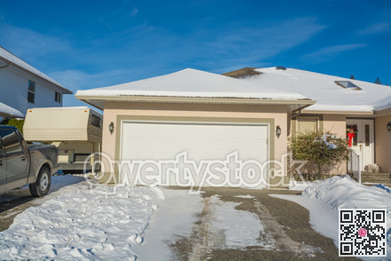 Wide garage of big luxury house with parked car and RV trailer on side