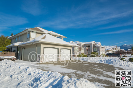 Double garage of big luxury house with driveway and front yard in snow