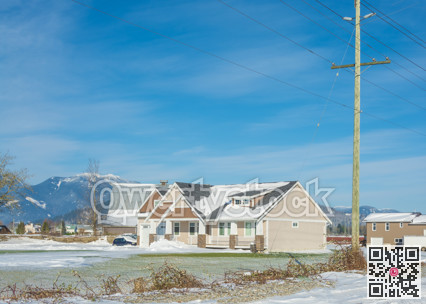Family house with mountain view and front yard in snow on winter sunny day