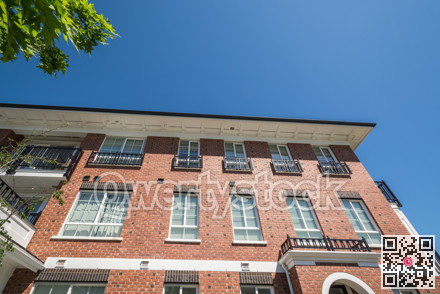 Top of new brick apartment building on blue sky background in British Columbia