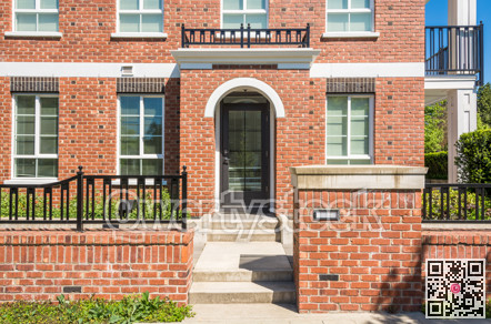 Entrance of new apartment building with concrete steps and brick fence in front