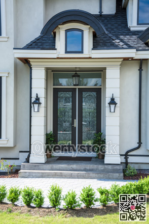 An entrance of a luxury house decorated with small trees in front.