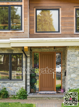 Wooden door of a house with pair of shoes and lilac watering can outside