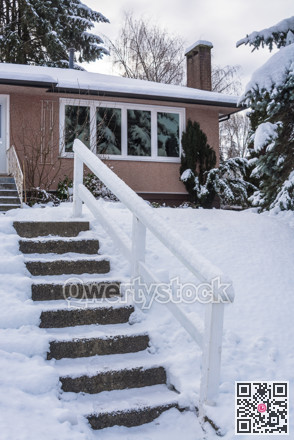 Stair way to the entrance of family house over front yard in snow