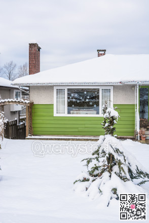 Entrance of residential house with front yard in snow on winter cloudy day