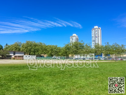 Modern cityscape with green lawn on bright sunny summer day.