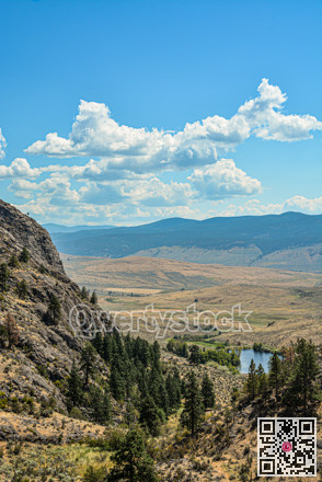 Scenery view of a valley with small lake downhill on bright sunny day