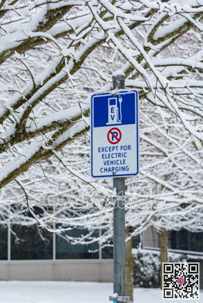Road sign with EV charging station on snow background