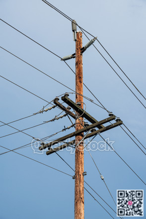 Electric pole and wires, wood electricty pole on blue sky background.