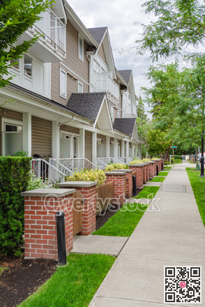 Row of townhouses with concrete pathway in front on couldy day in Vancouver, BC