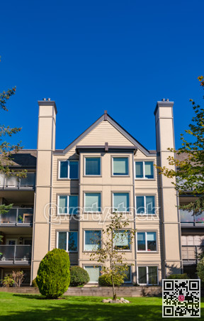Apartment building with green lawn in front on bright sunny day