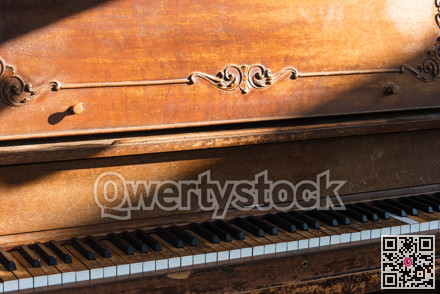 Open keyboard of street piano in sunlight ray.