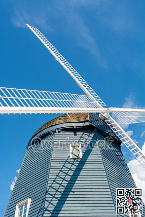 Vintage wind mill decorated with lights on blue sky background.