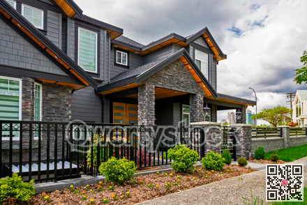 Luxury residential house with front yard behind metal fence