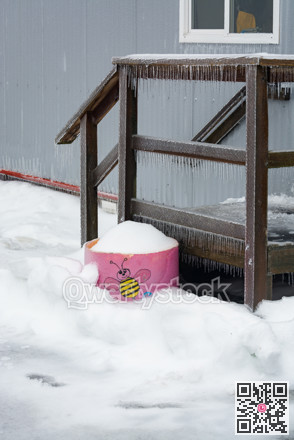 Ice covered doorsteps of portable building with pink flowerbed on side