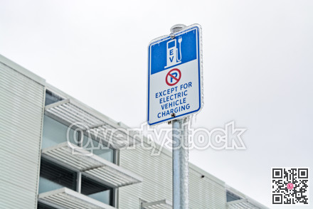 EV charging station sign in icicles and office building on the background