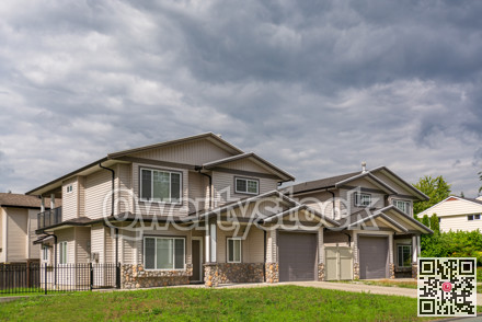 Residential duplex building with concrete driveway and green lawn in front