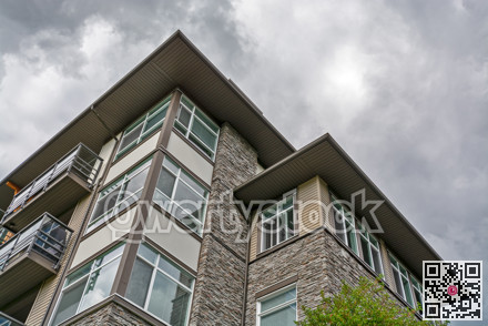 Top of residential building with stone texture wall on cloudy sky background.