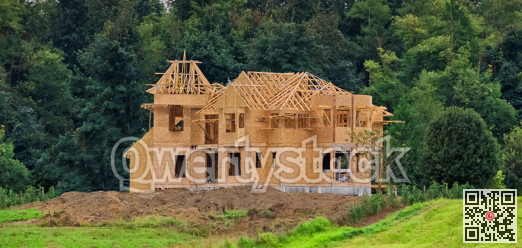 Wooden framework of the building on green lush background.