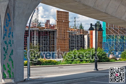 City street with the building construction and rail transportation above