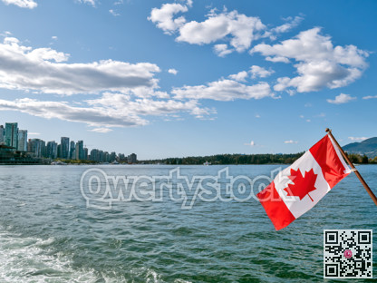 Canadian flag on blue sky and water background in Vancouver harbor