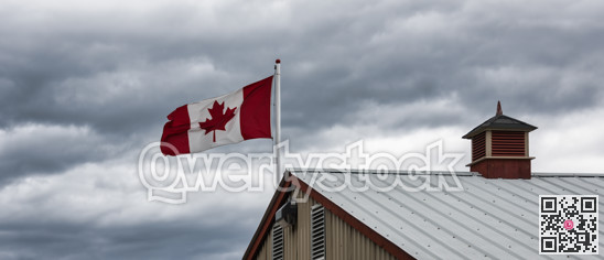 Canadian flag above the roof on stormy sky background