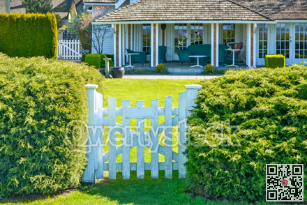 White wooden entrance gate leading to a front yard patio