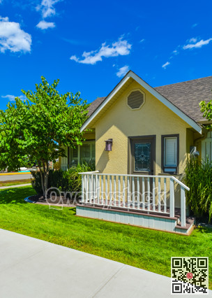 Small yellow family house on sunny day with green lawn and concrete pathway