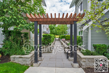 Walkway in residential area between two rows of townhouses with unit for sale