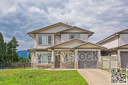 Half of residential duplex building with concrete driveway and lawn in front