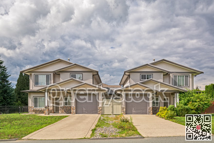 Residential duplex building with concrete driveway and green lawn in front