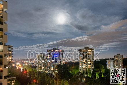 Night cityscape with full moon in clouds