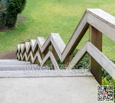 Zig-zag railings of wooden stairway on green grass background